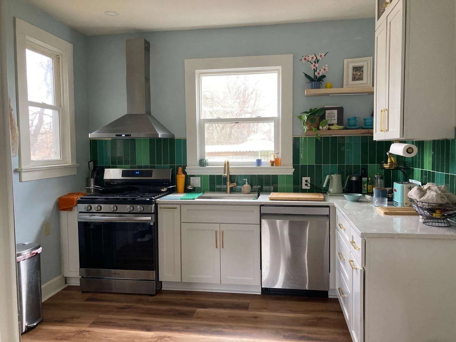 A kitchen with white shaker cabinets and a green tile backsplash