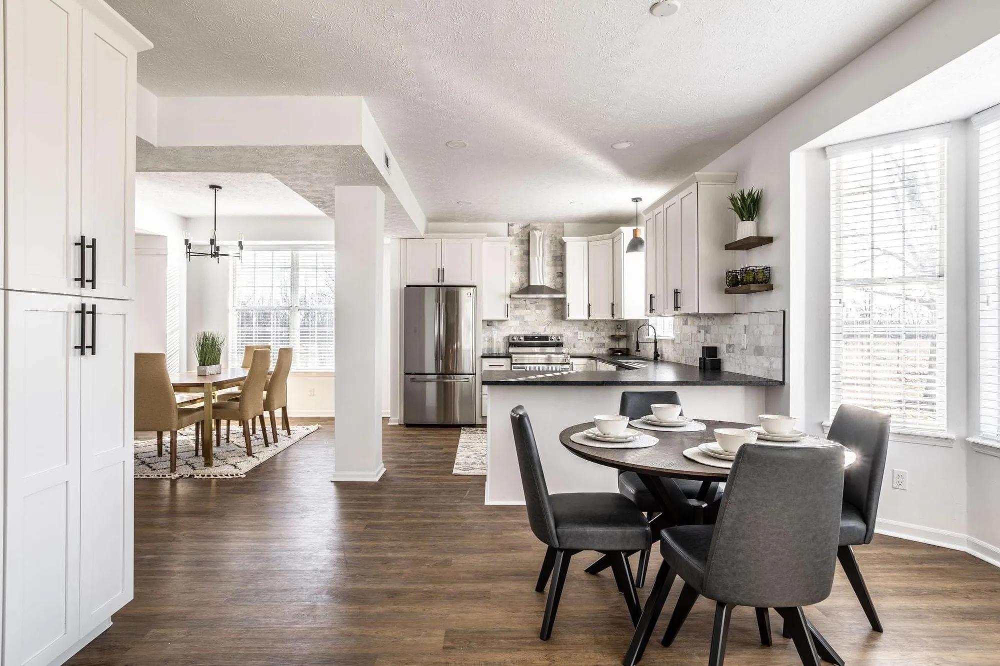 An open kitchen and dining room with white cabinets and dark counters